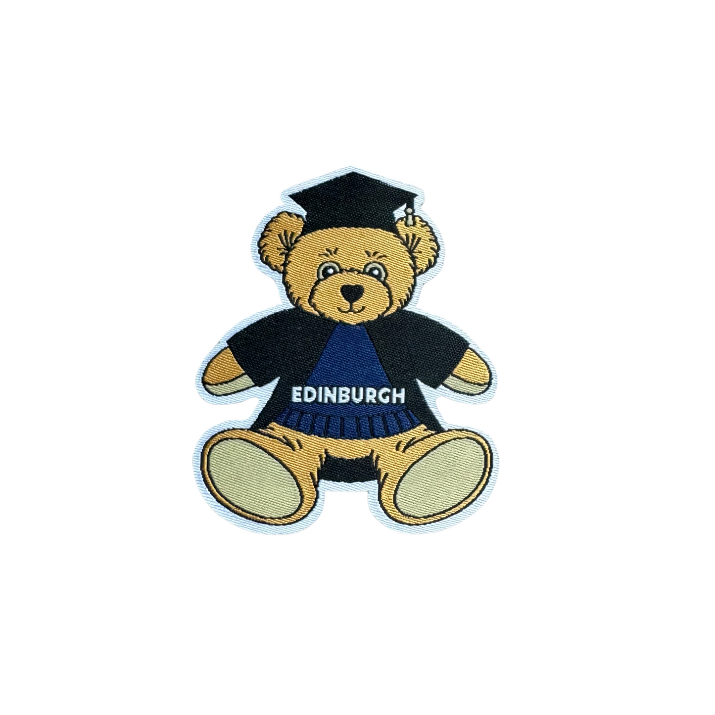 Close up of Edinbear patch. Edinbear is a light brown teddy wearing a graduation cap and gown, over the top of a blue sweater that says 'Edinburgh'.