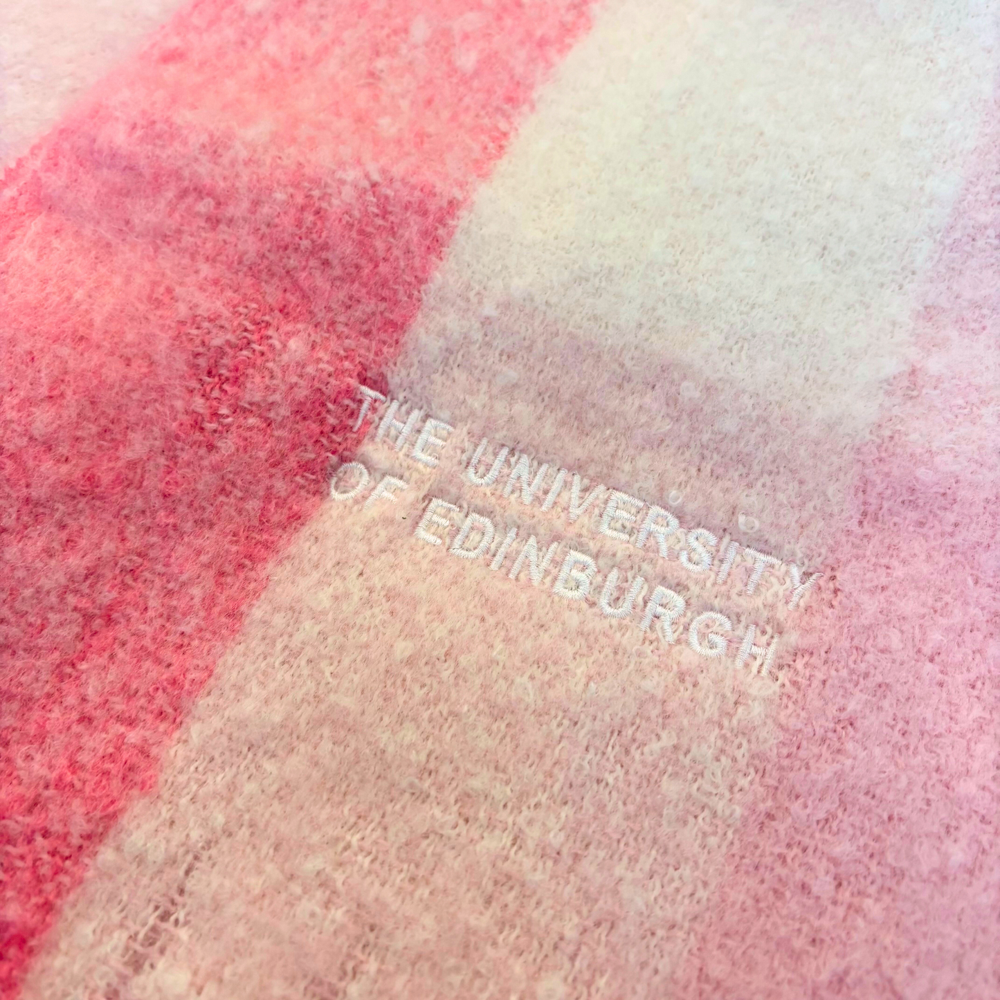 White 'THE UNIVERSITY OF EDINBURGH' embroidery on the pink check scarf.