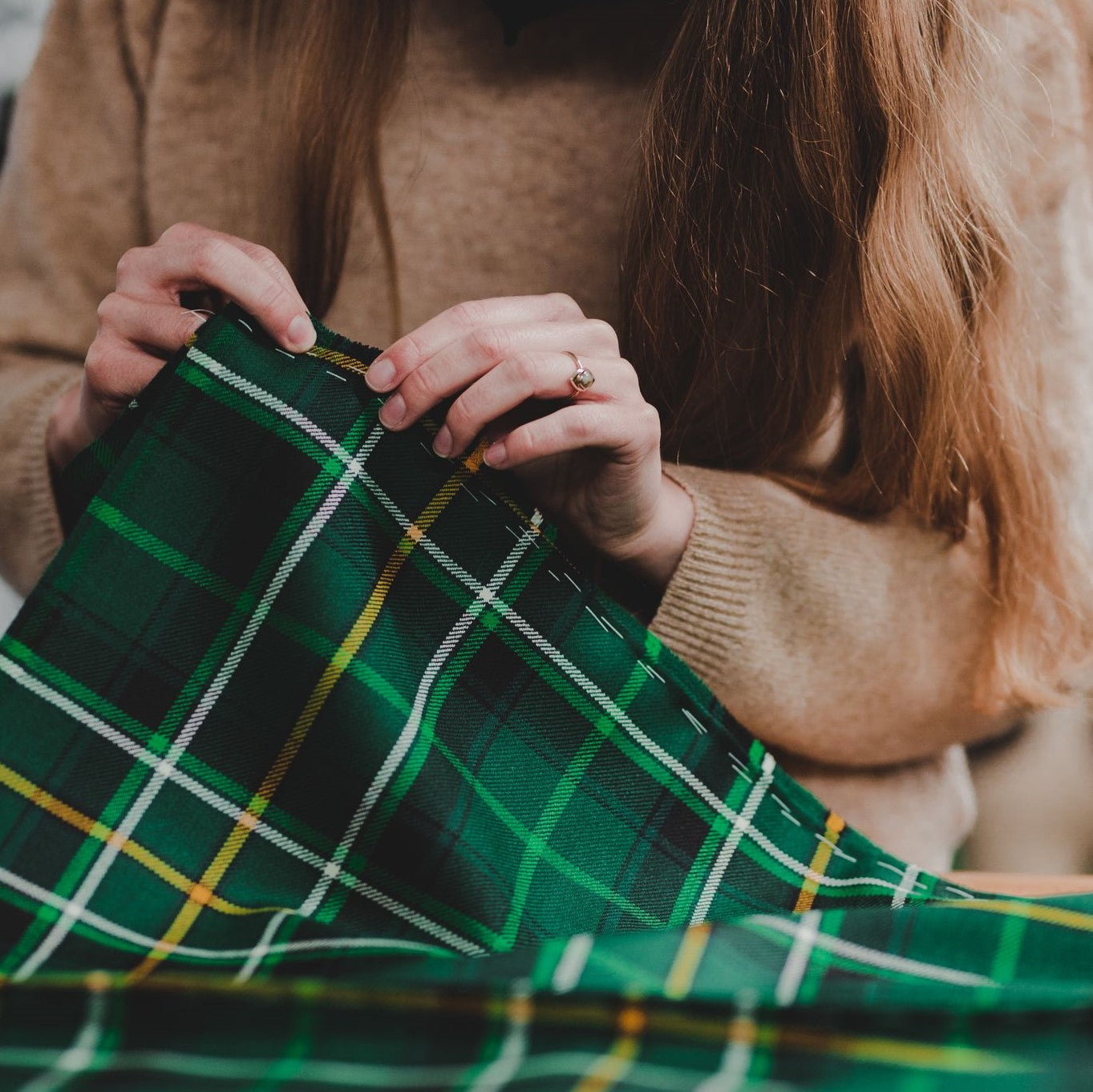 Hand-stitching green tartan fabric