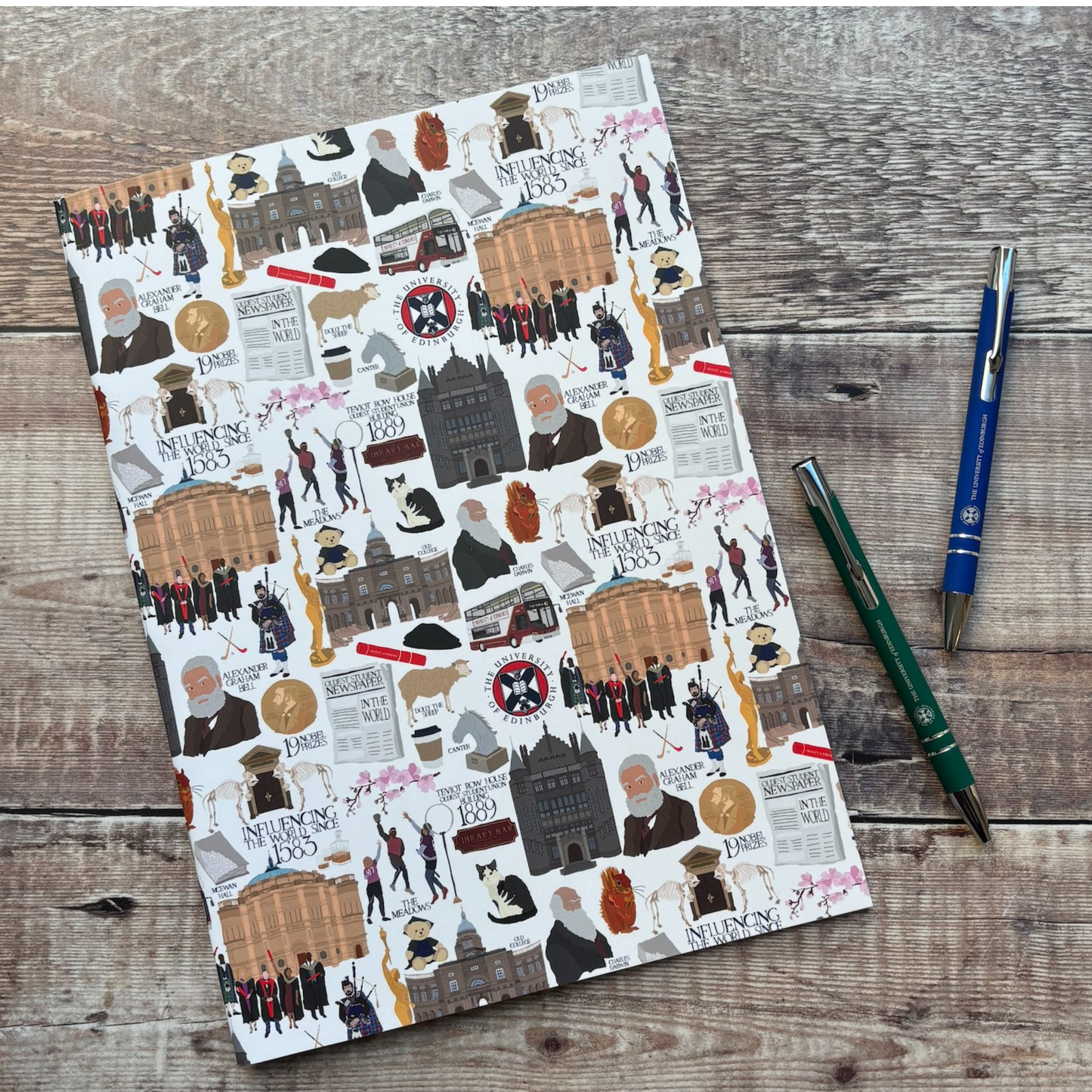Our A4 Heritage Collection notebook. It is white with various illustrated figures and images associated with the University of Edinburgh. Illustration by Designed by Esther.