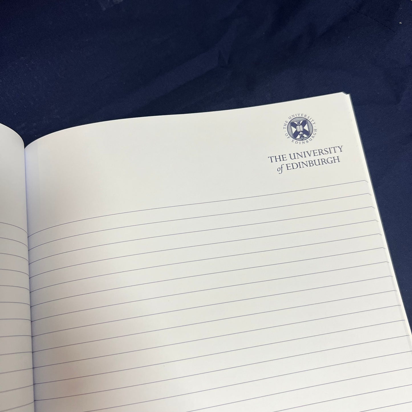 White notebook with lined pages featuringthe university logo