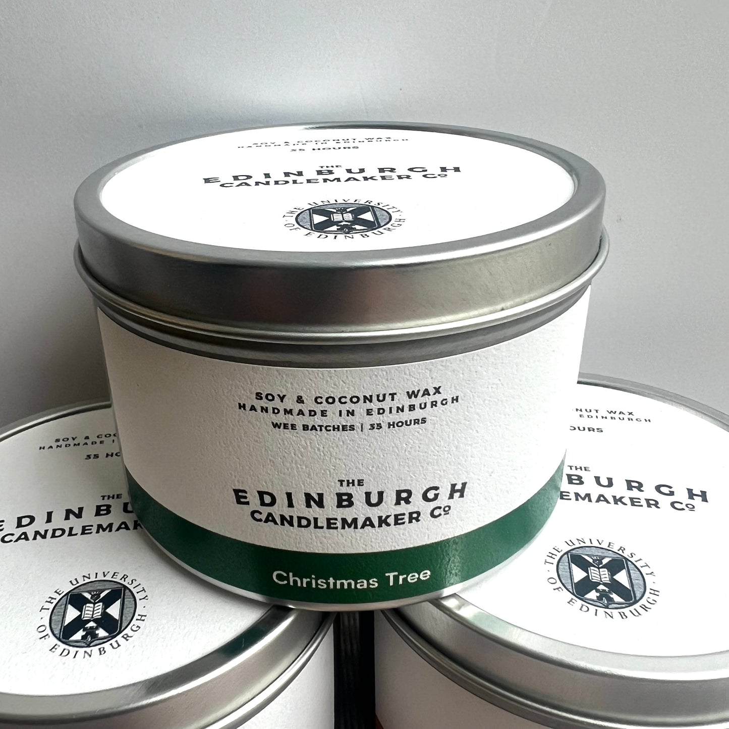 christmas tree candle in silver tin with white label.