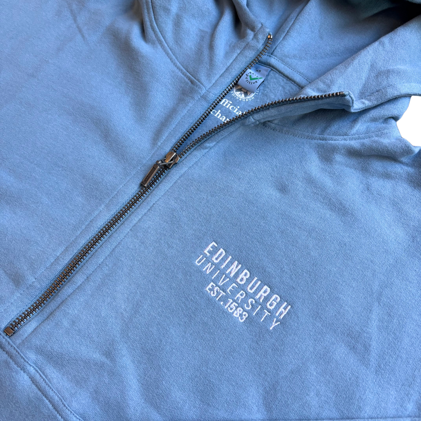 Close up of the white embroidery on the blue hoodie.