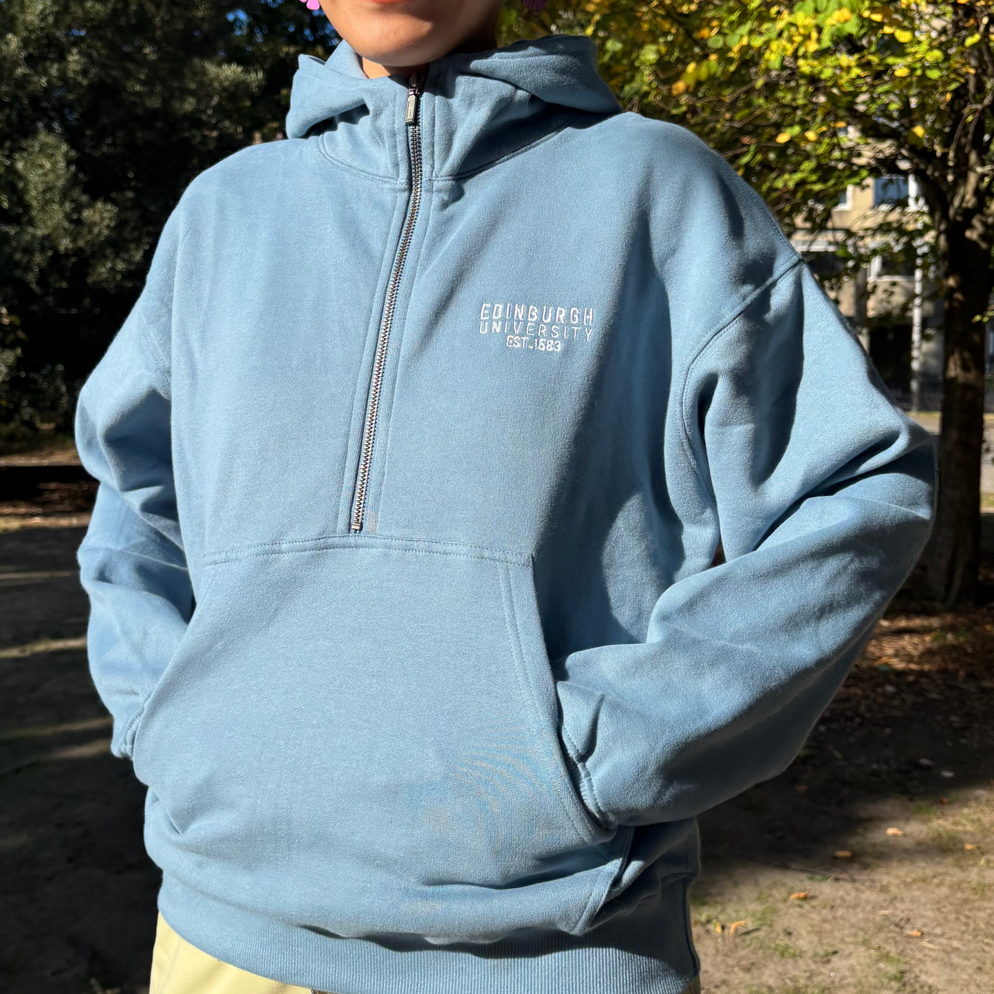 Model puts hand in the pockets of the Premium Embroidered Half-Zip Hoodie.