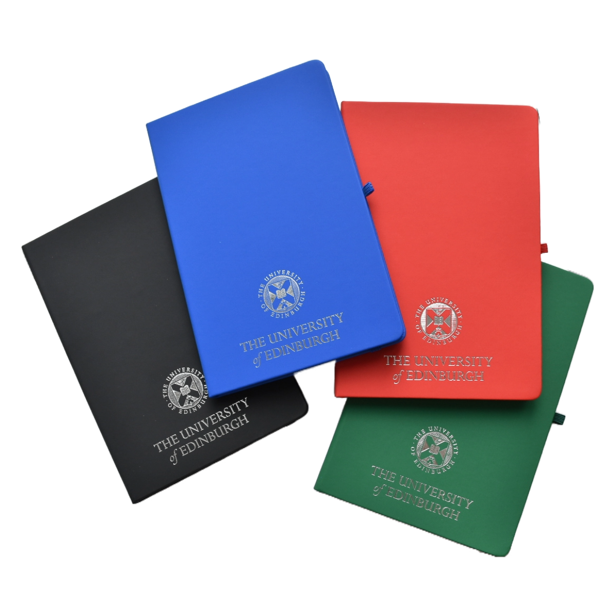 A collection of A5 size notebooks in red, blue, black, and green, each featuring a silver foil design of the university crest.