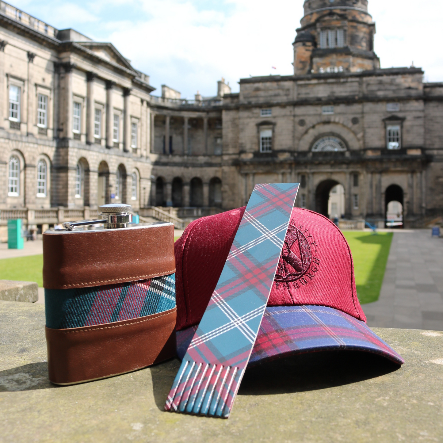 The Leather and Tartan Hip Flask, Leather Tartan Bookmark and Tartan Baseball Cap in Burgundy pictured in the Old College Quad.