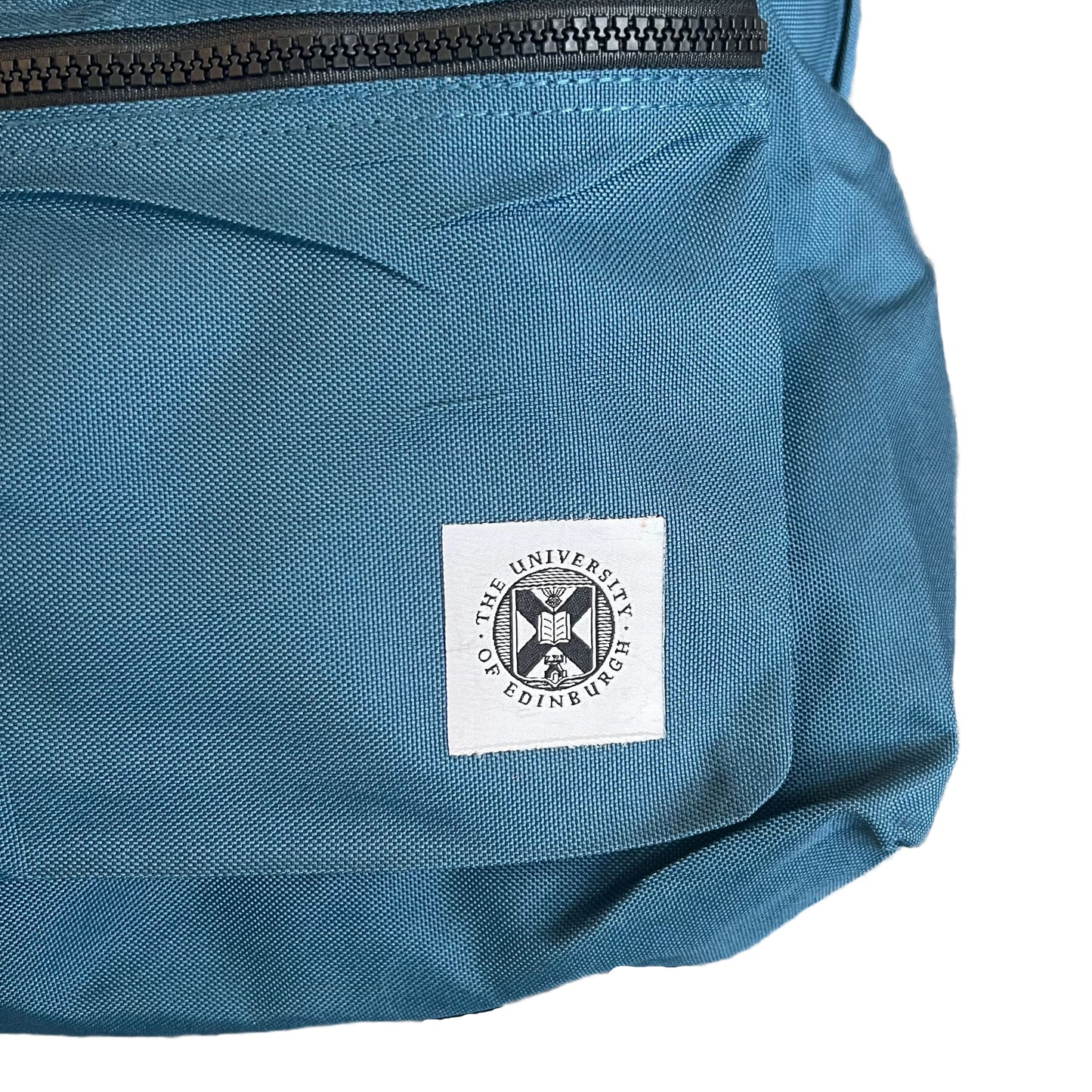 Close up of the University of Edinburgh's crest stitched onto a blue backpack.
