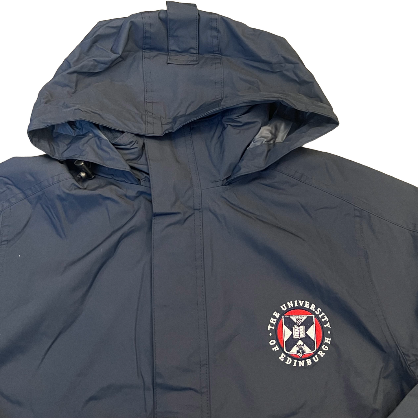 navy waterproof jacket with hood up, with the University crest embroidered on the left chest in white, red and navy