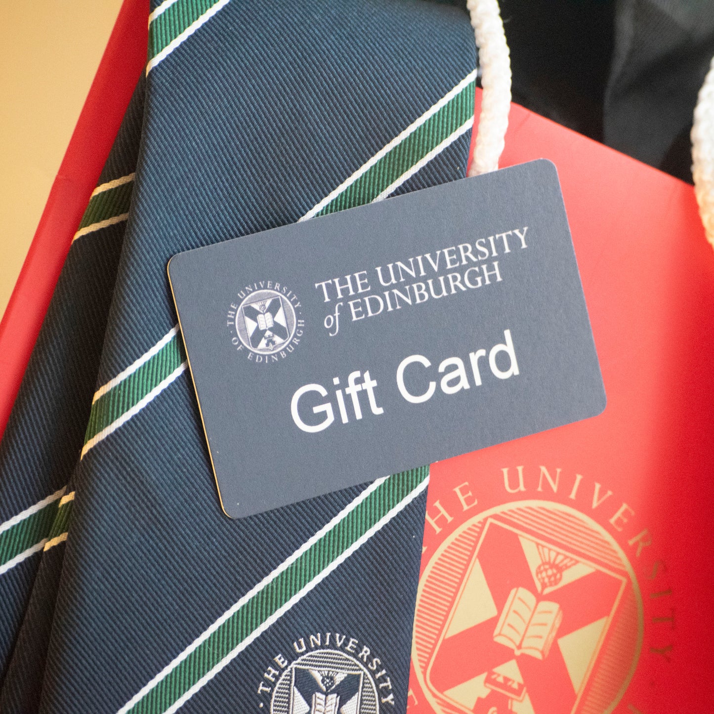 One of our gift cards against a backdrop of our Green and Navy Striped tie and one of our Gift Bags.