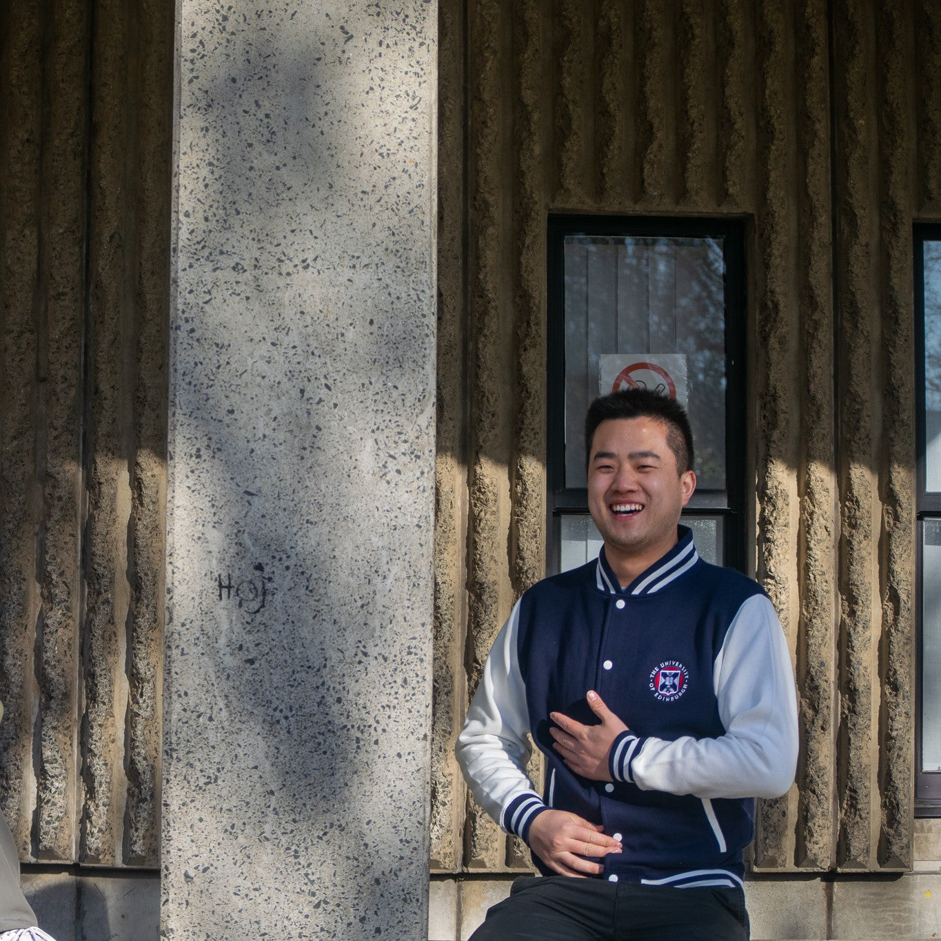 Model wearing varsity style baseball jacket in navy