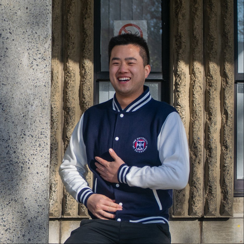 Model wearing varsity style baseball jacket in navy