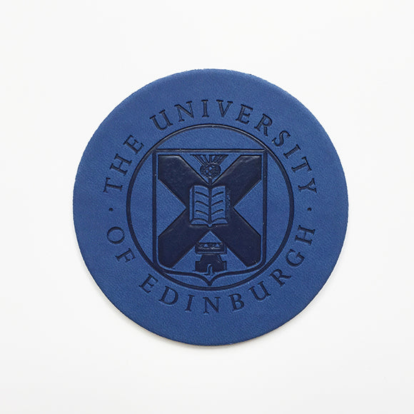 Front view of a leather coaster with embossed University crest in blue