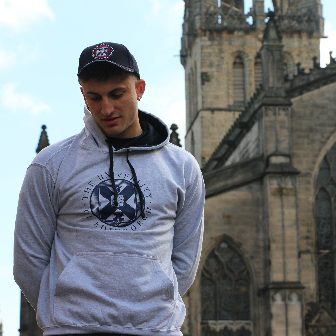 Our model wears Classic Crest Baseball Cap in Navy and Large Crest Two Tone Hoodie in Grey