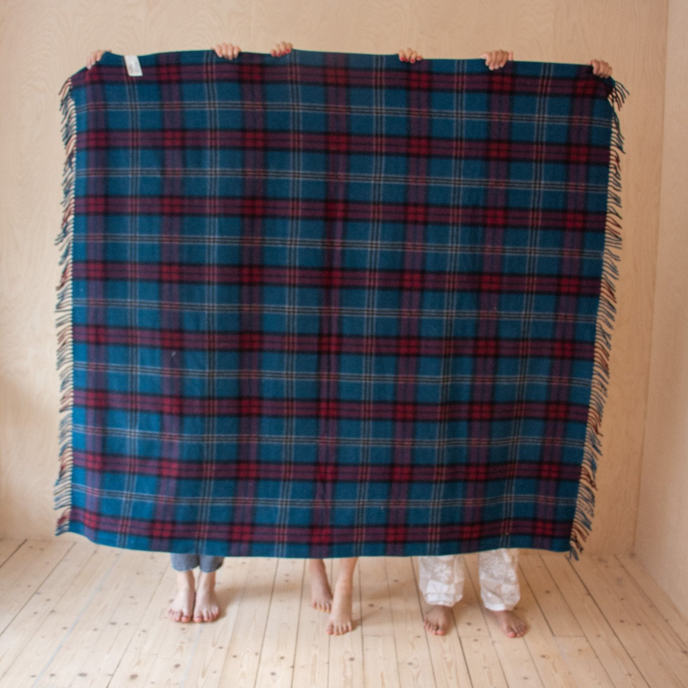 full size university tartan blanket being held by 3 people