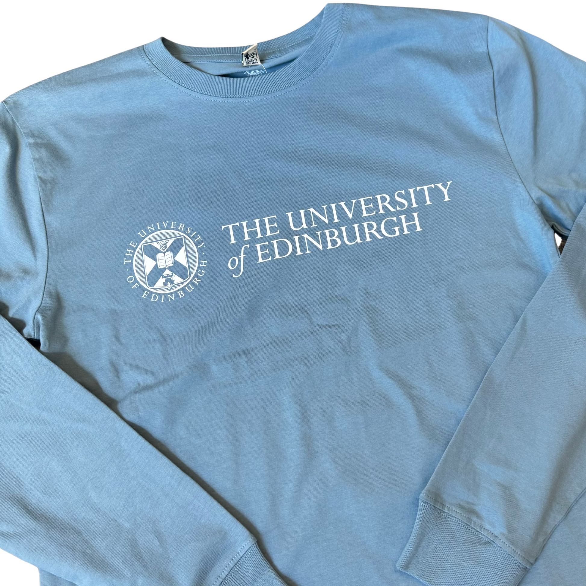 Close up view of the University Classic Logo on our stone blue long sleeve with cuffed sleeves.