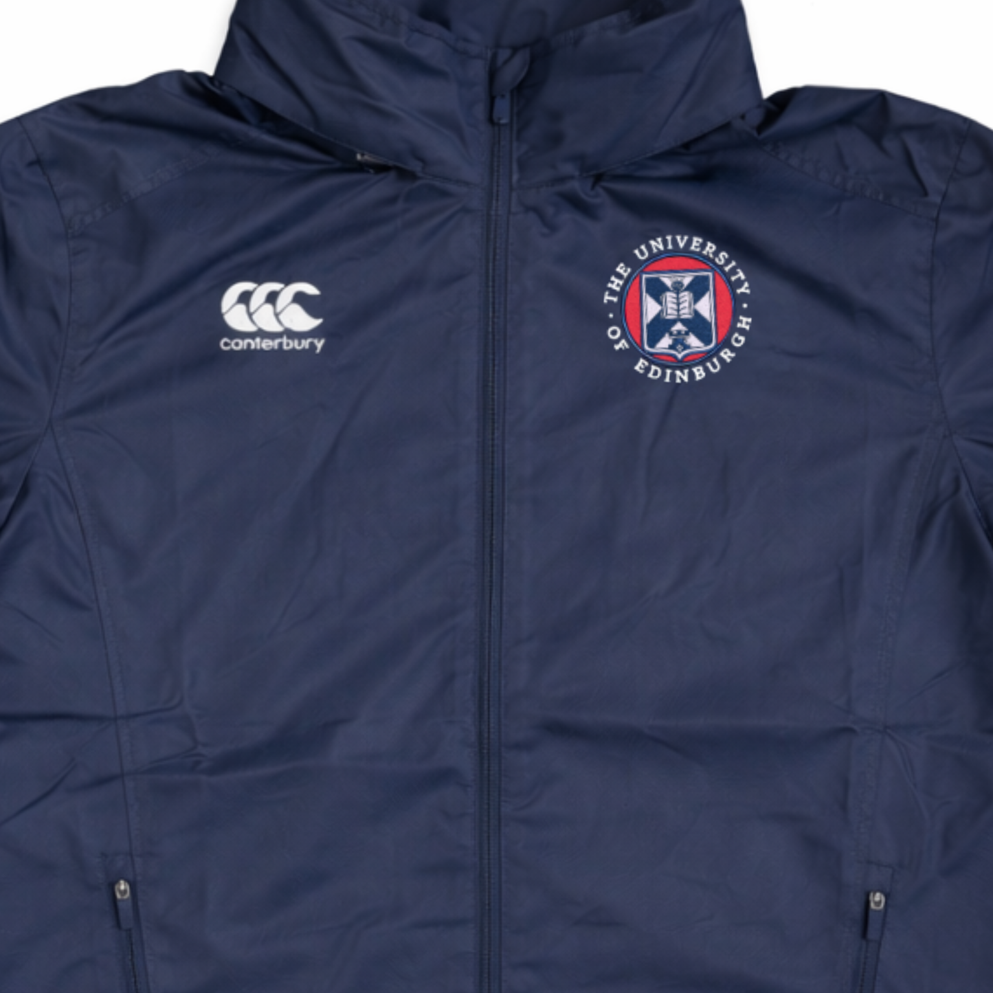Close up of navy Vaposhield jacket with Canterbury logo on left chest and University of Edinburgh crest embroidered on the right chest.