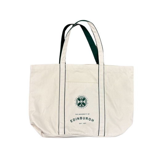 A cream-colored canvas tote bag featuring the University of Edinburgh crest and 'THE UNIVERSITY OF EDINBURGH EST. 1583' text in green. The bag has two sturdy handles with a dark green inner lining and vertical green piping accents. The design is printed on an exterior slip pocket on the front.