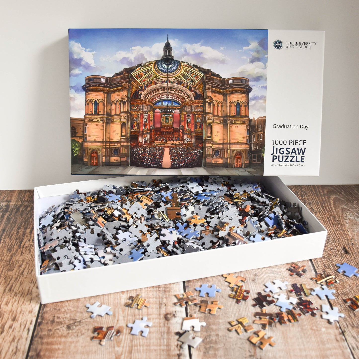 Image of open puzzle box with the pieces inside, puzzle pieices are also scattered around box.