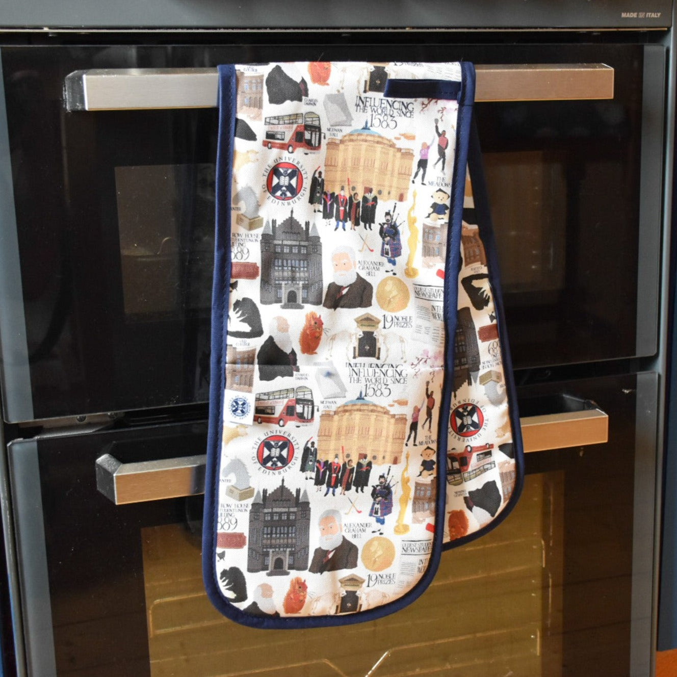 Oven gloves with illustrations of various University of Edinburgh icons, buildings, and figures, pictured with oven.