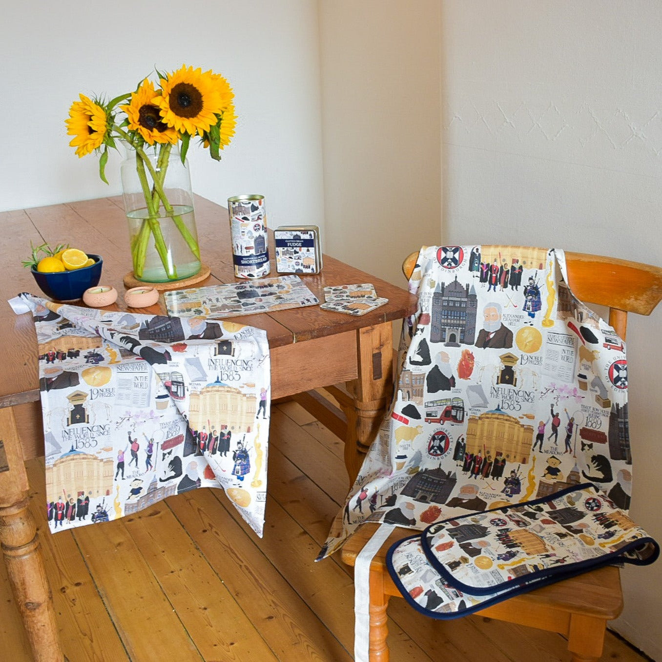 Visual presenation of Heritage Collection items, including: Clotted Cream Fudge, Scottish All Butter Shortbread, Placemat, Coaster, Apron, Oven Gloves and Tea Towel.