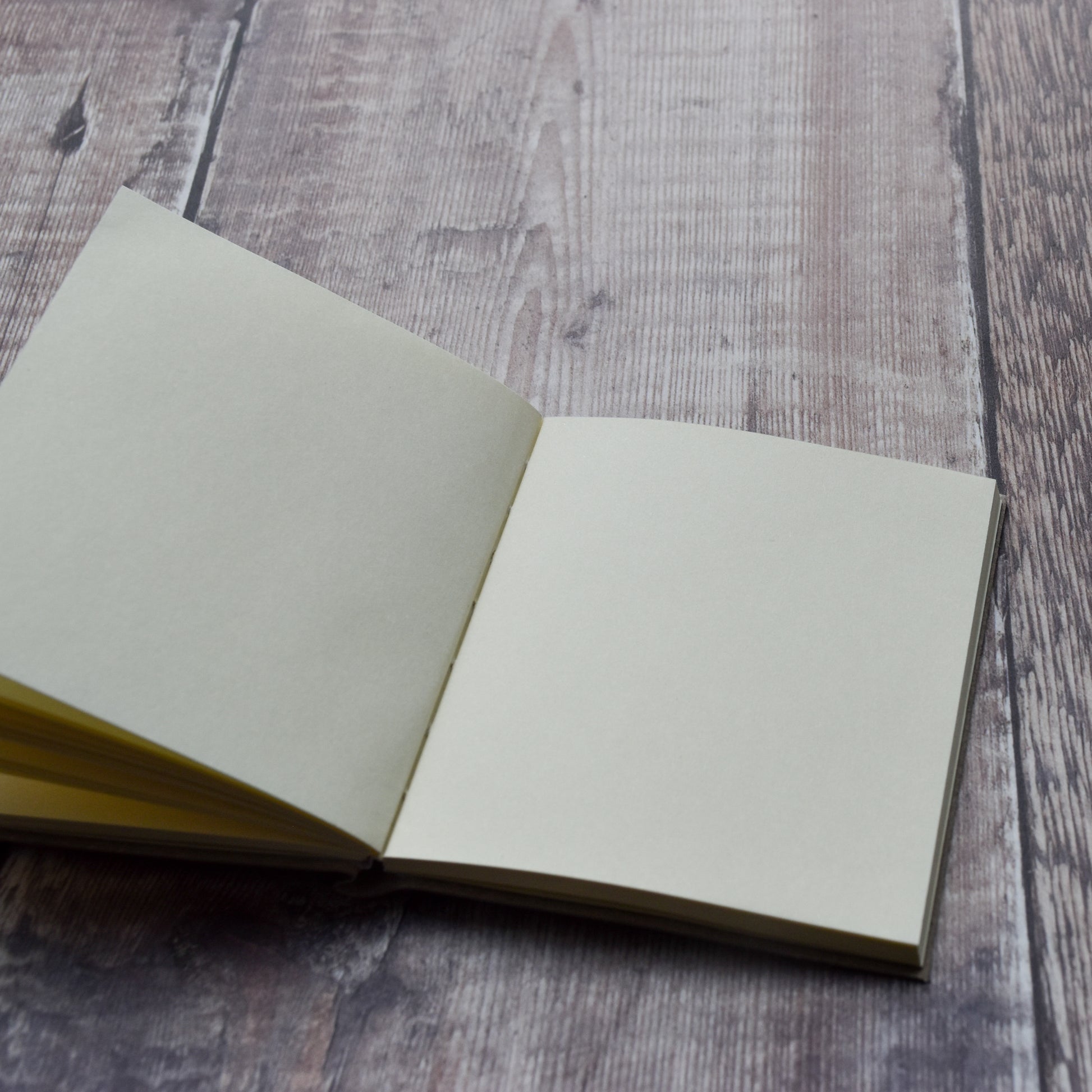 The Graduation Day Notebook open to a blank page on a grey wooden background.