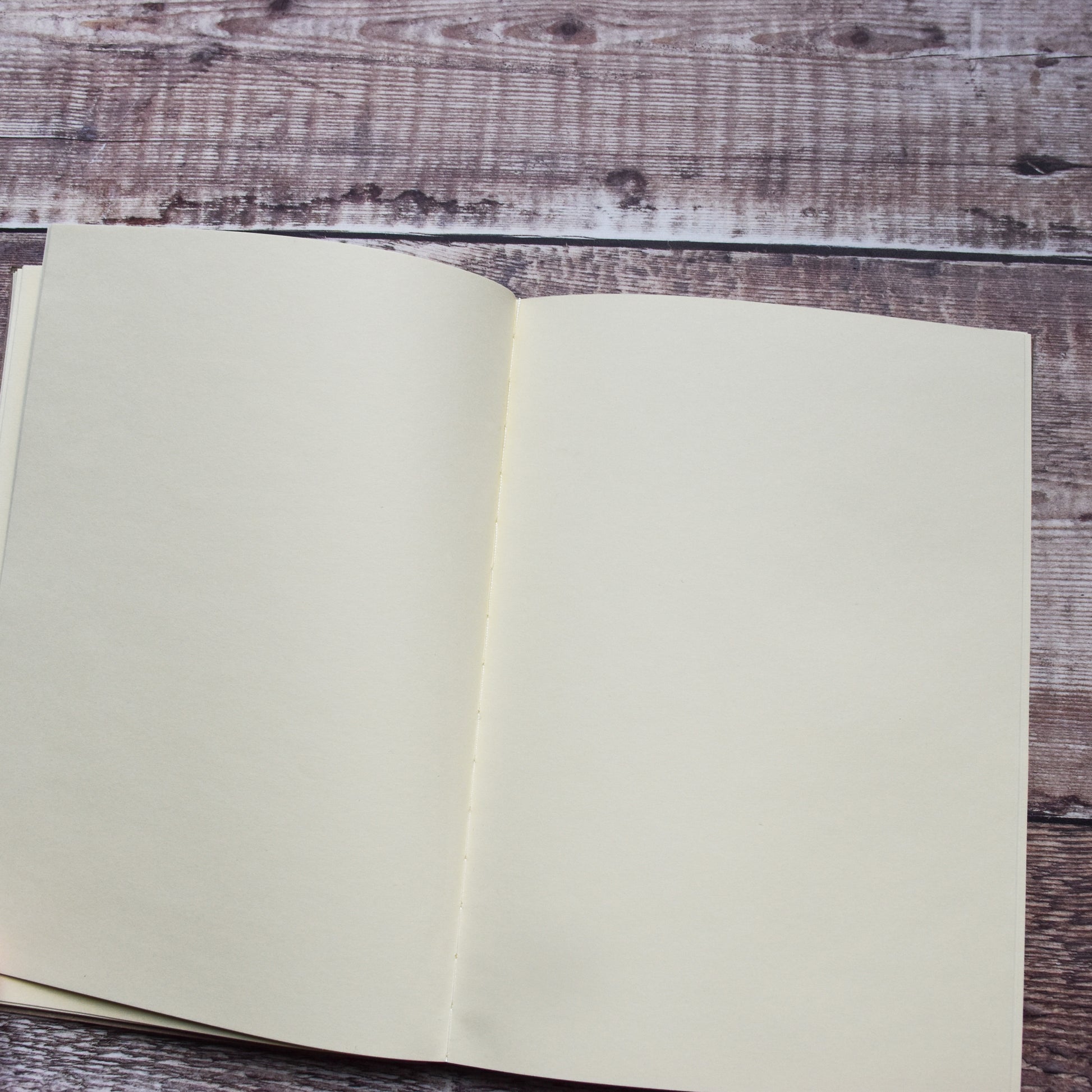 A close up of a blank open page within the A5 Heritage Collection Notebook on a brown wooden background.
