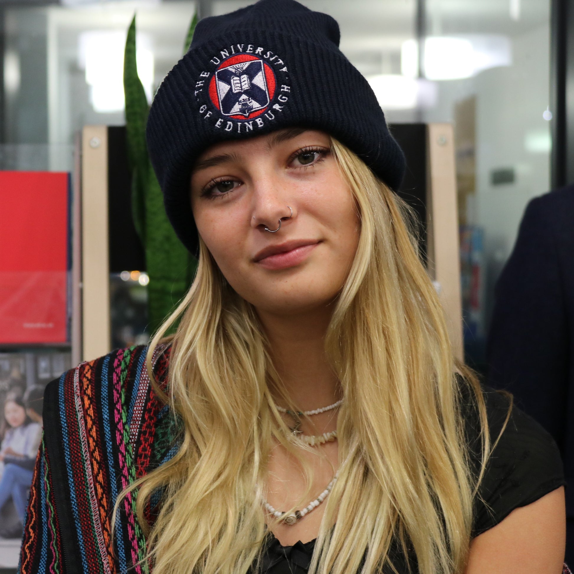 model wearing navy ribbed cotton beanie with an embroidered red, white, and navy university crest