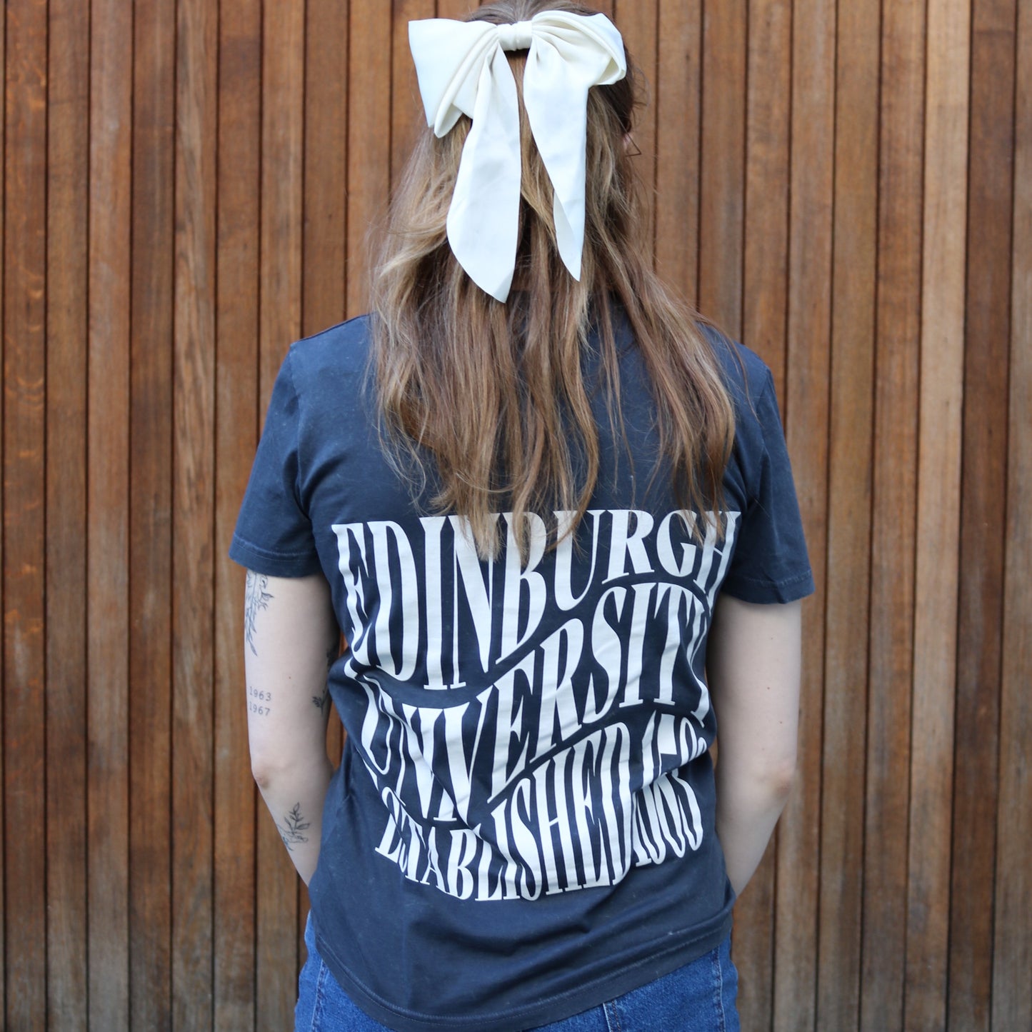 Kirstie modelling the back of the distressed charcoal vintage tee shirt. 'Edinburgh University Established 1583' text is printed in white and in a wavy pattern across the back of the shirt.