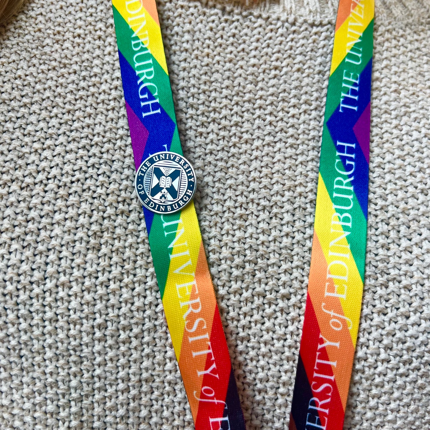 navy and silver crest pin badge on progress rainbow lanyard