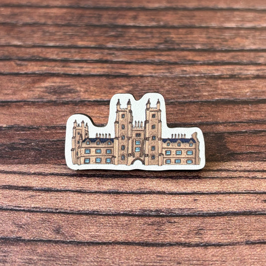 The New College wooden pin badge.