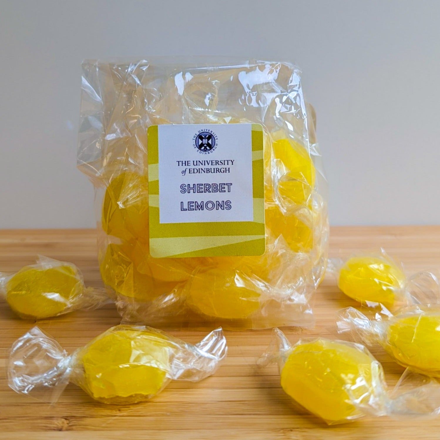 Close up of a plastic bag of Sherbet Lemon candies. A few wrapped candies are scattered in front of the bag. The University of Edinburgh's Crest is on the candy label.