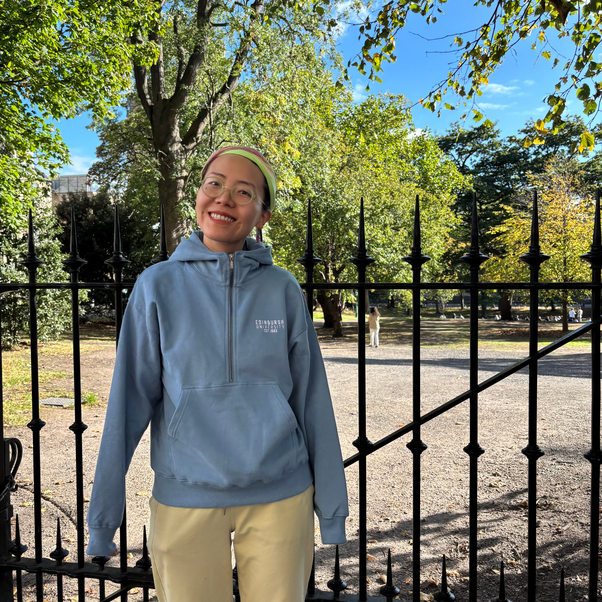 Model wears Premium Embroidered Half-Zip Hoodie in George Square Gardens.
