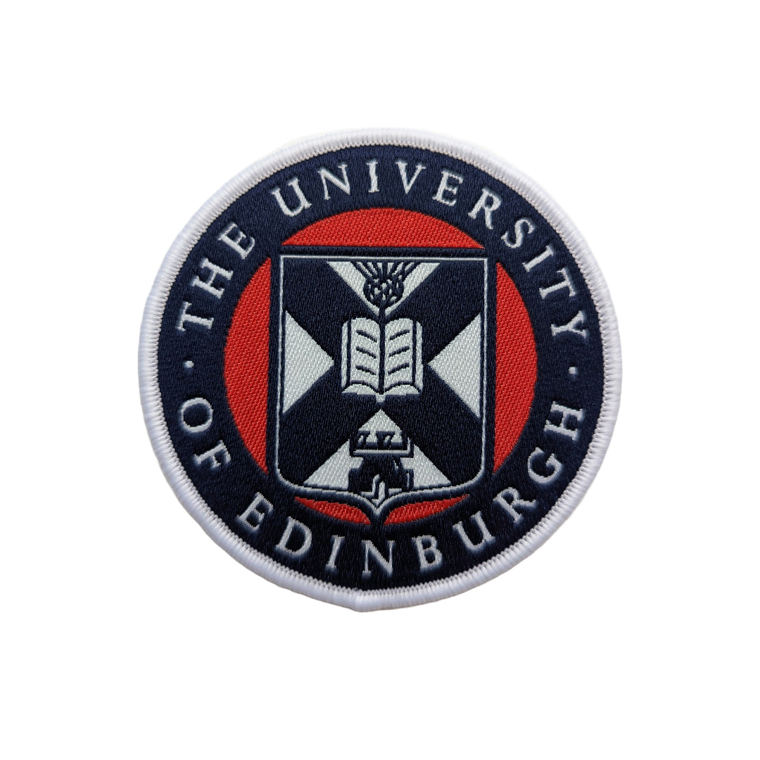 close up of navy, red, and white university crest woven patch on a white background