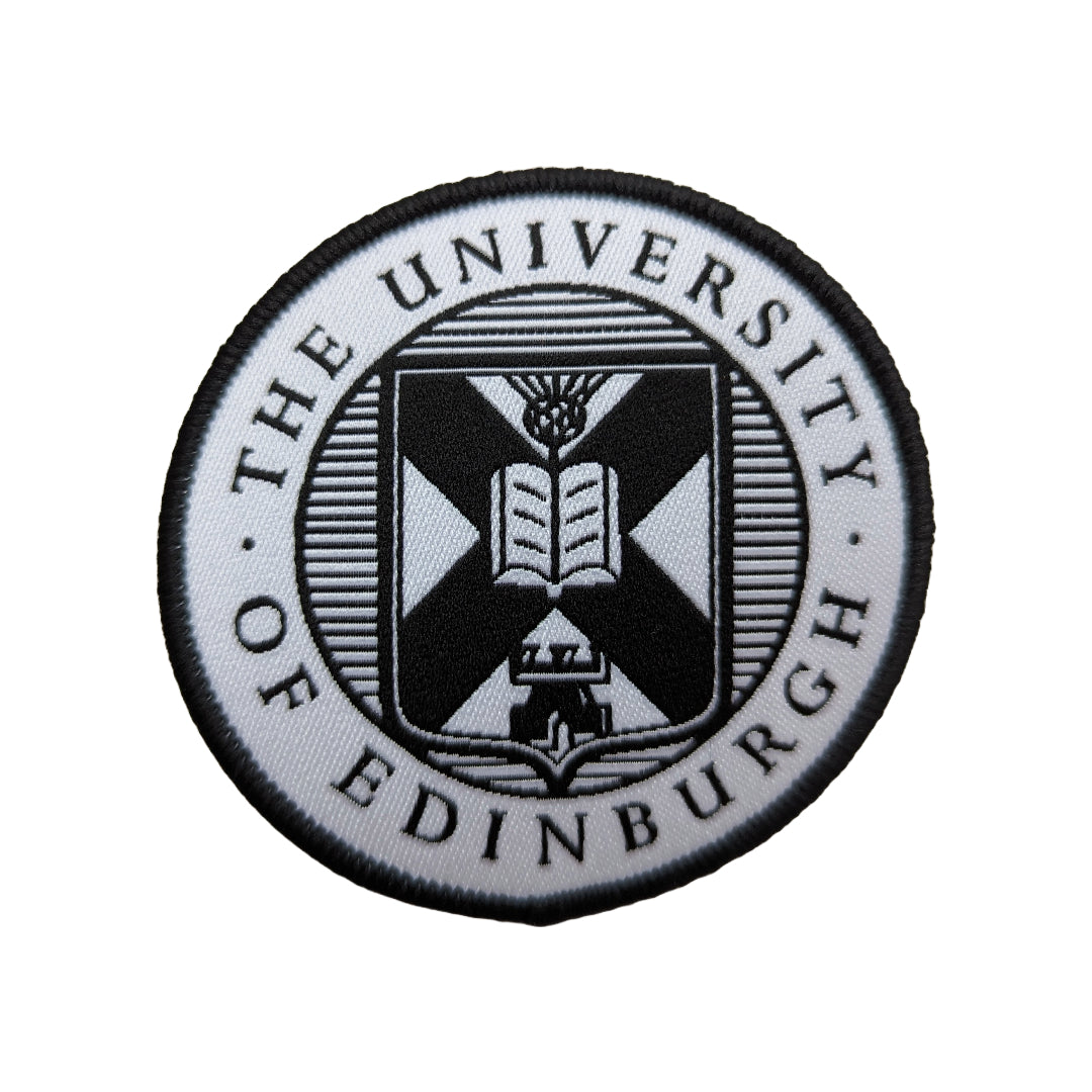 close up of black and white woven university crest patch on a white background