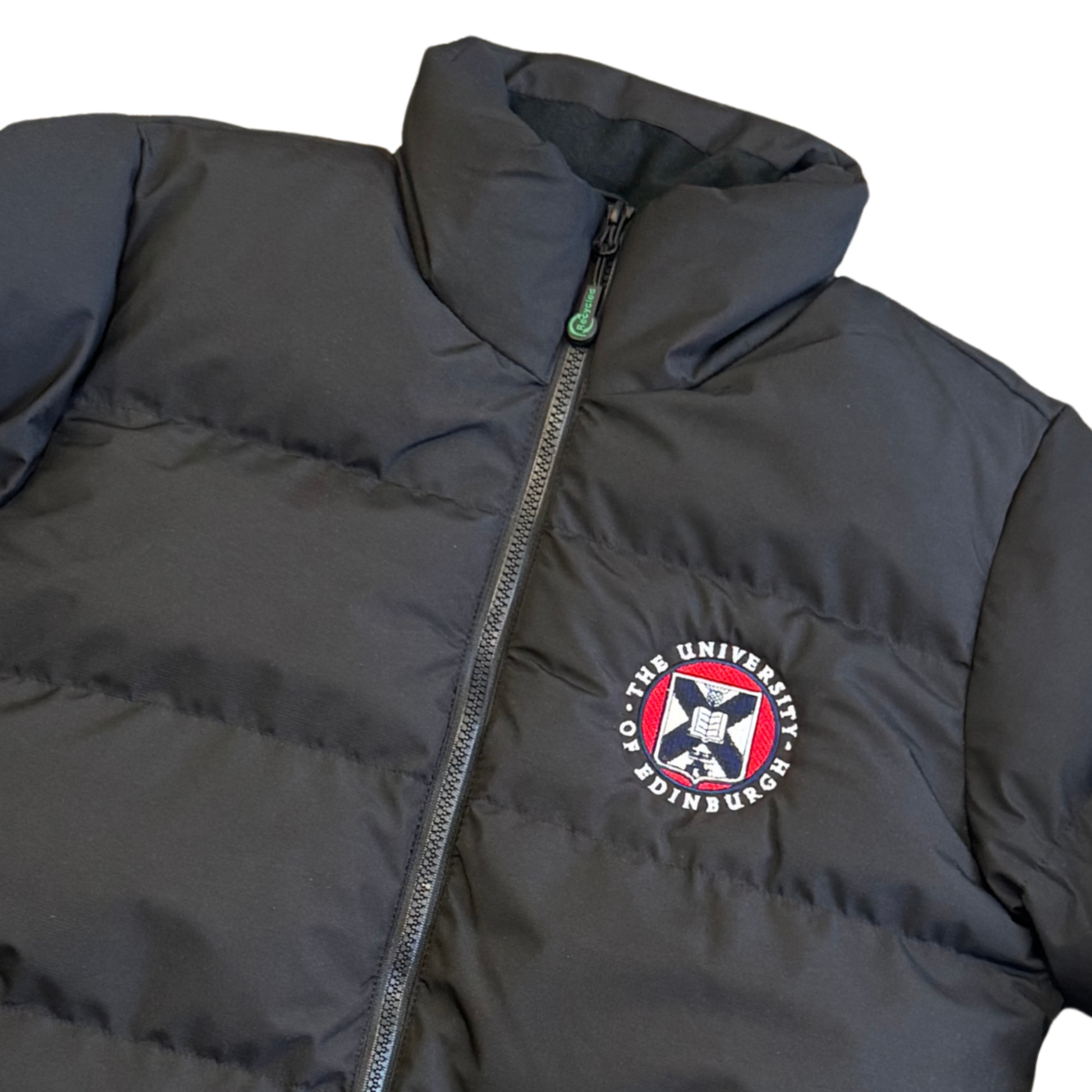 Full zip black puffer with collar, zip pockets, and adjustable cuffs. Features full colour university crest.