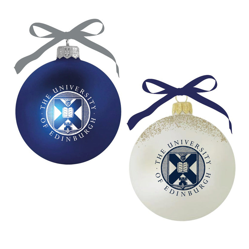 A white bauble with a navy University of Edinburgh crest and gold glitter, tied with a navy ribbon and a navy bauble with a white University of Edinburgh crest tied by a white ribbon. 