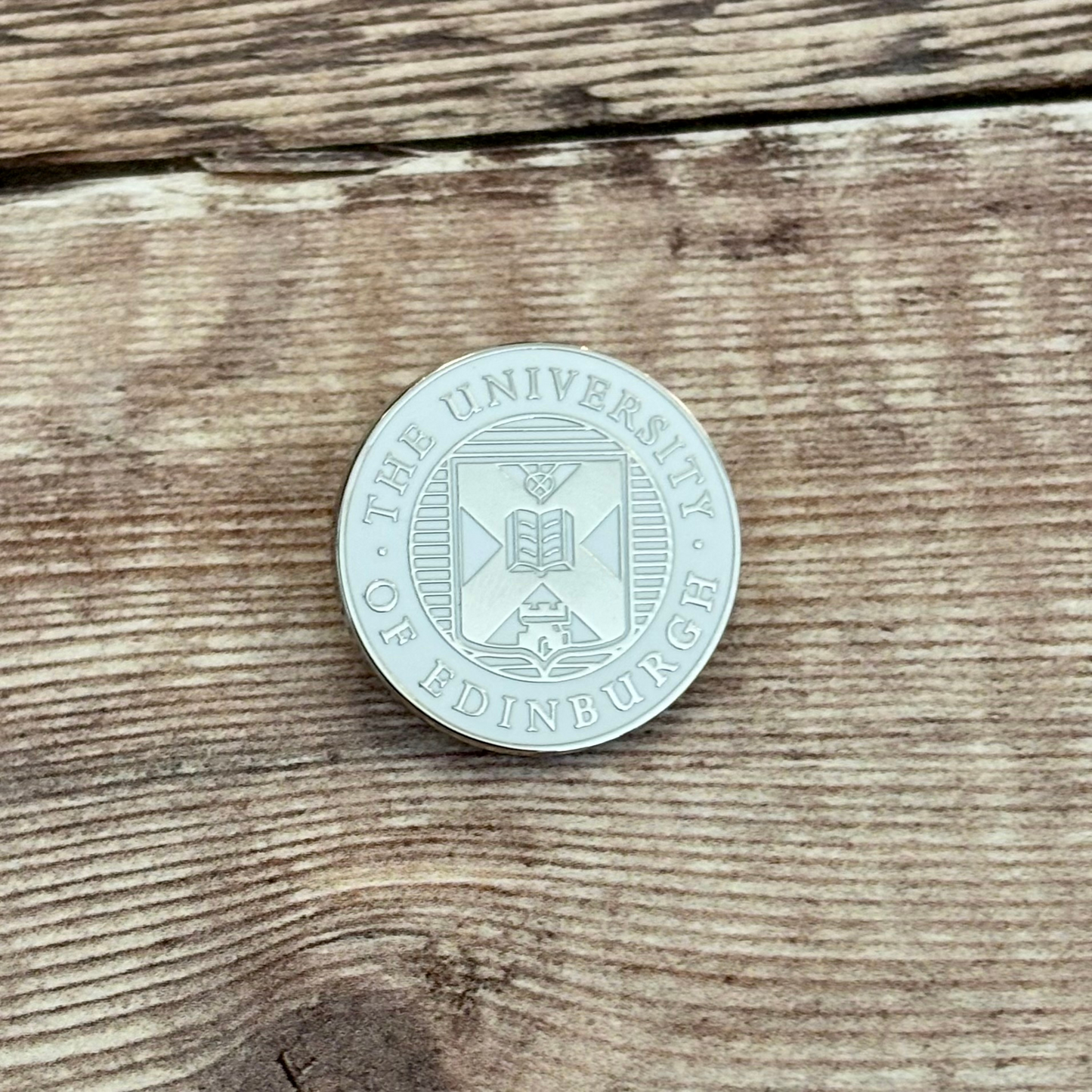 Silver and white crest pin badge.
