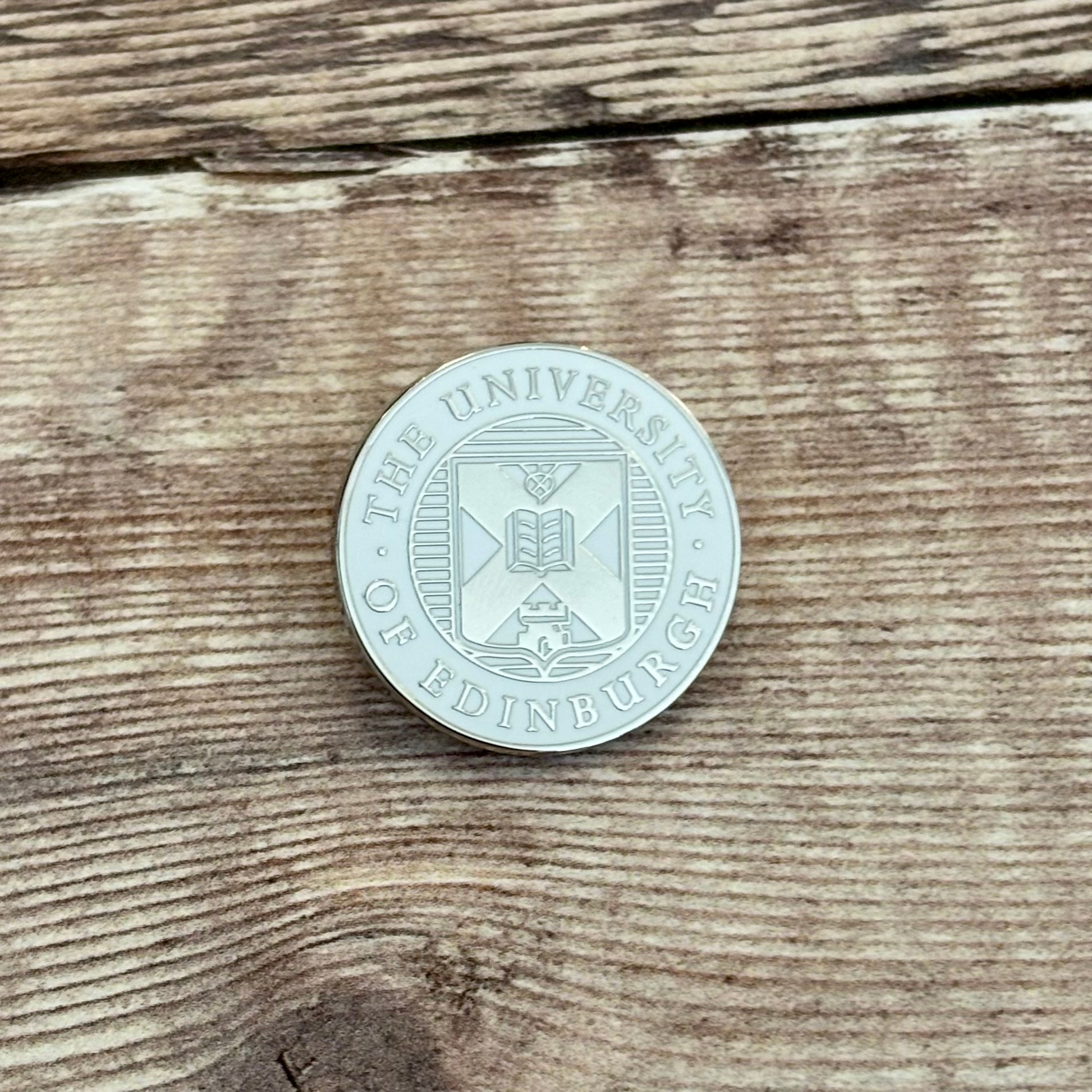 Silver and white crest pin badge.