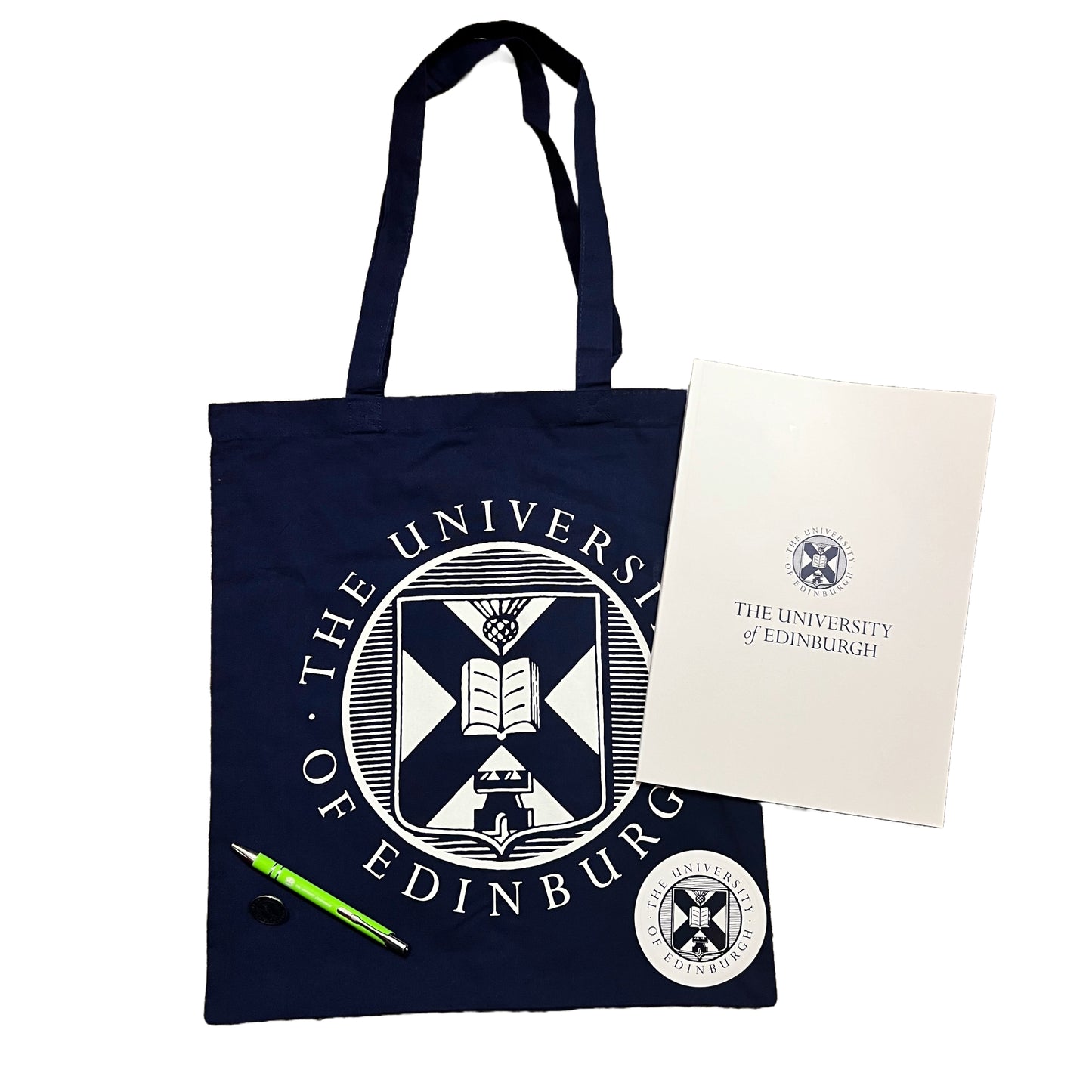 Navy tote bag with white university crest, white a4 notebook with navy crest, wihite and navy crest laptop sticker, green pen and navy crest pin badge
