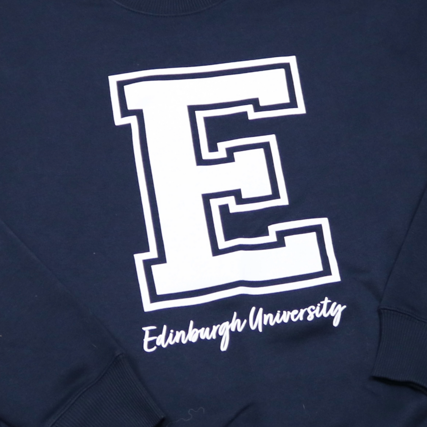 close up of the white printed varsity letter E and cursive edinburgh university below