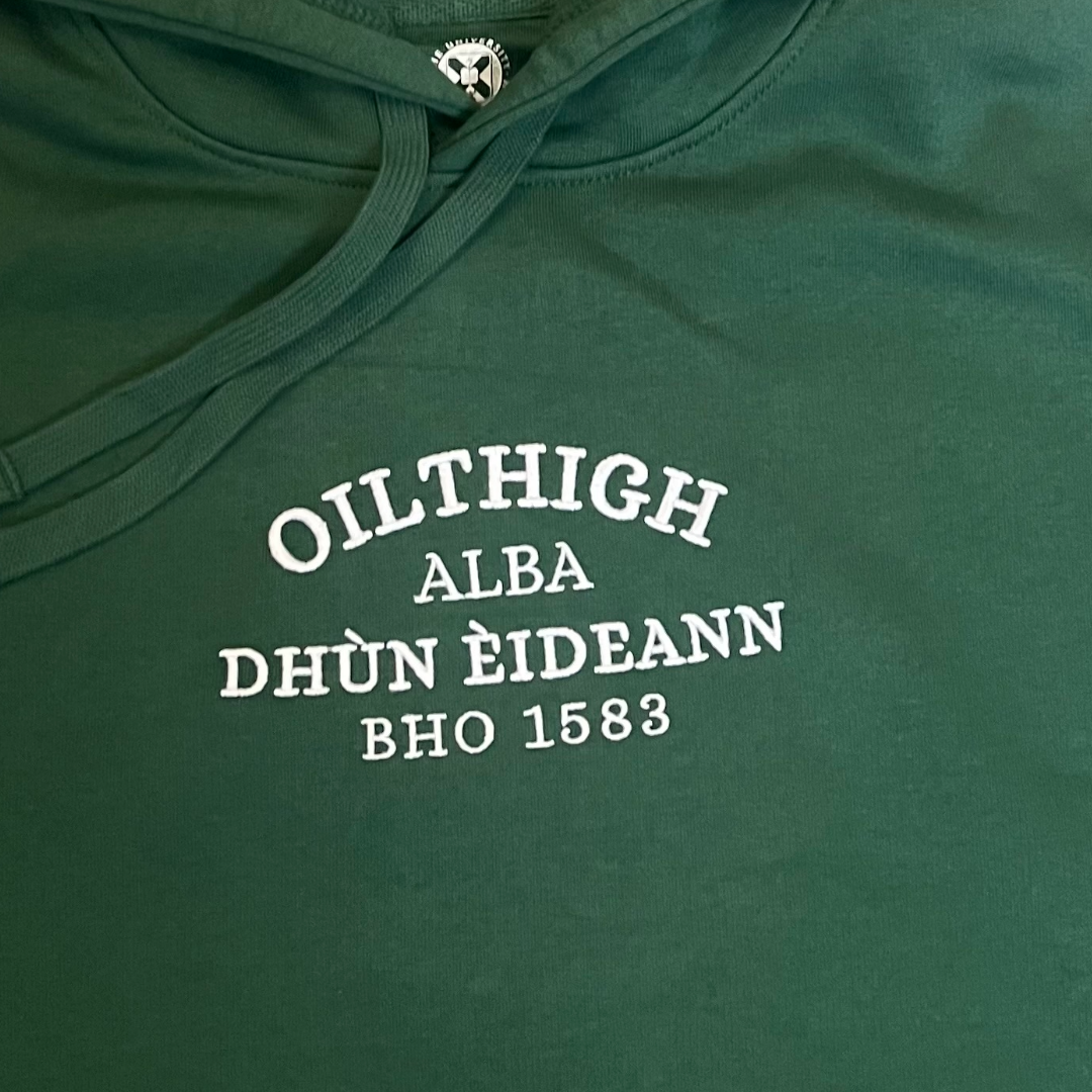 close up of Green Hoodie with Oilthigh Dhùn Èideann, Alba, Bho 1583, embroidered in white