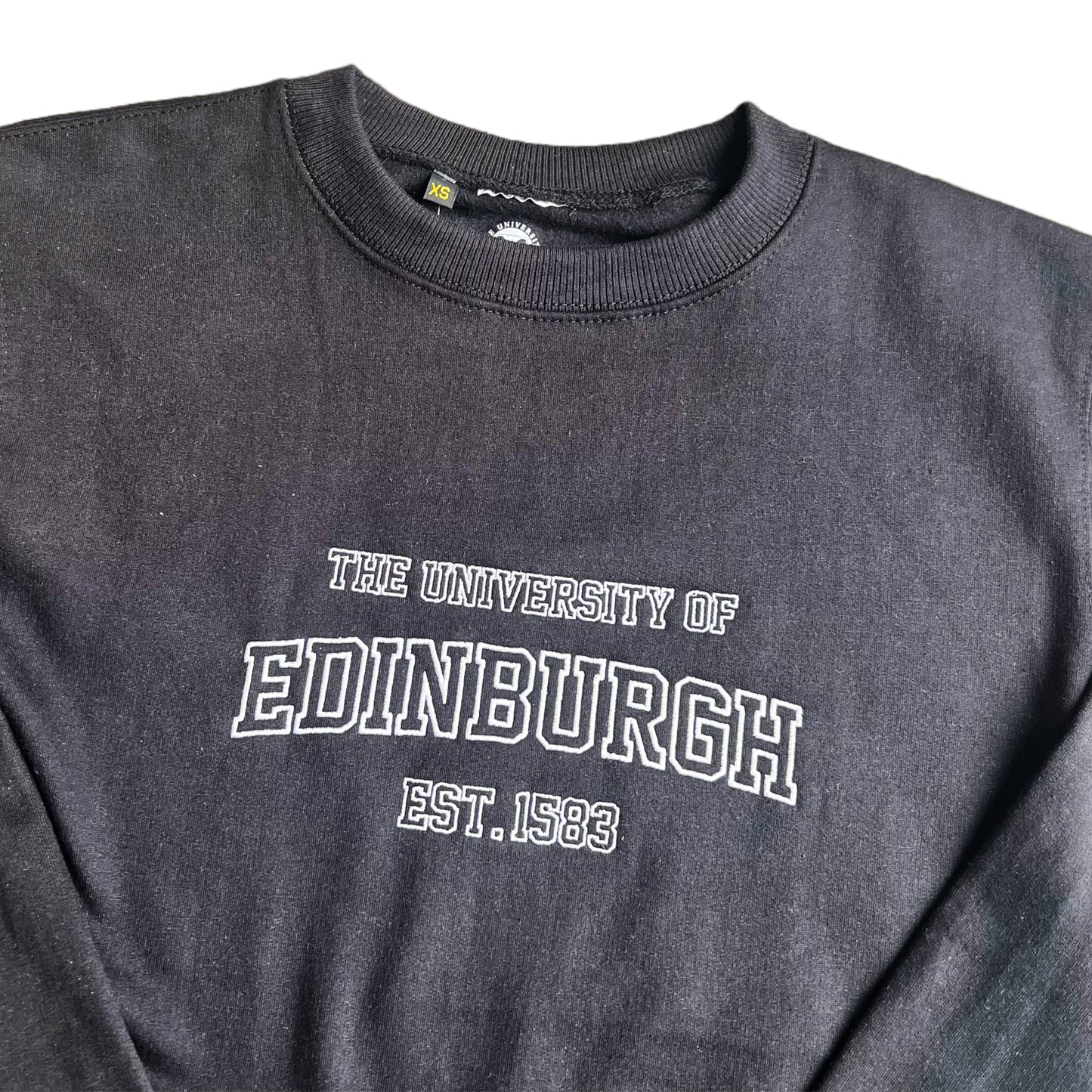 Close up of white embroidered text reading 'the University of Edinburgh EST. 1583' on a black sweatshirt.
