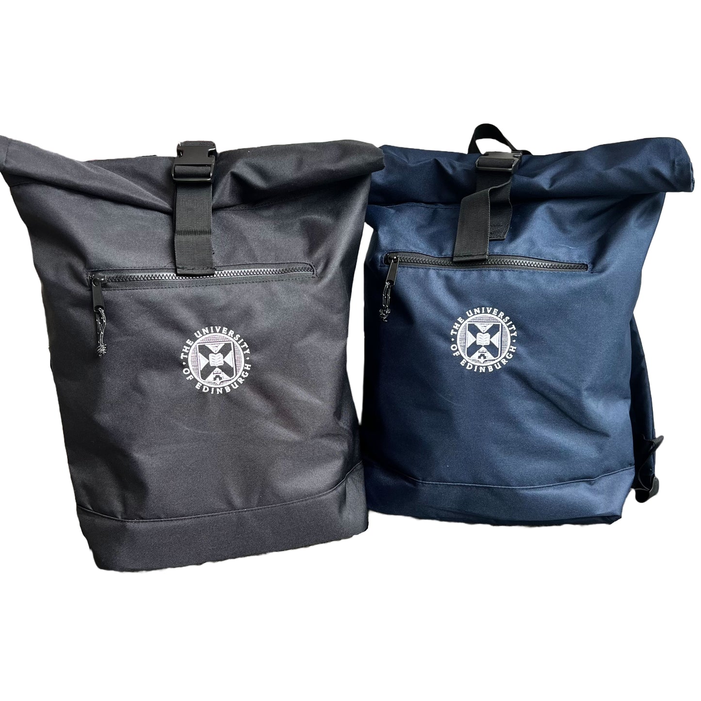 Two roll-top backpacks with University of Edinburgh crest stitched on the centre in white. One backpack is navy and the other backpack is black. The backpacks have a zipped pocket at the front.