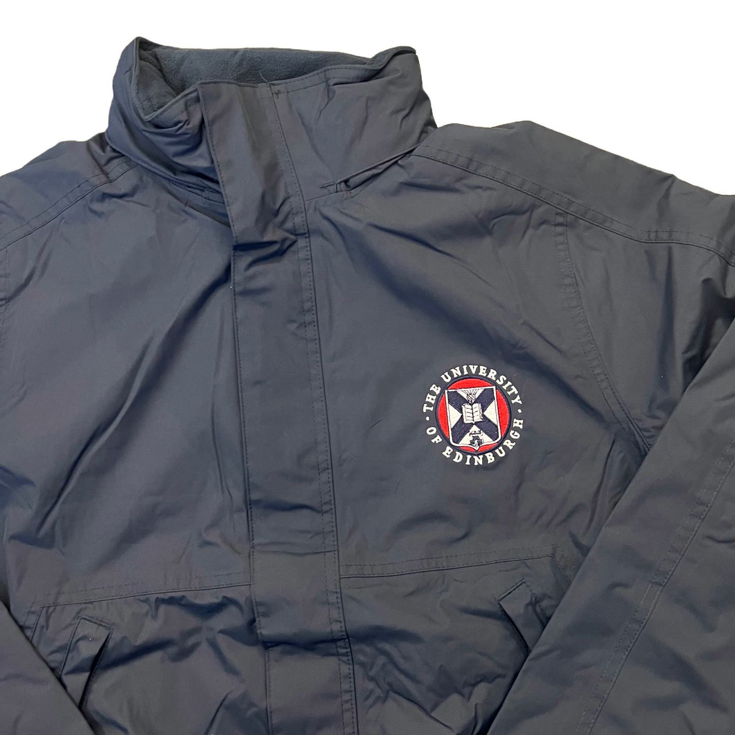 navy waterproof jacket,  with the University crest embroidered on the left chest in white, red and navy 