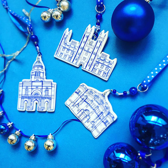 Three different ceramic decoration on a blue background, featuring Old College, New College and McEwan Hall