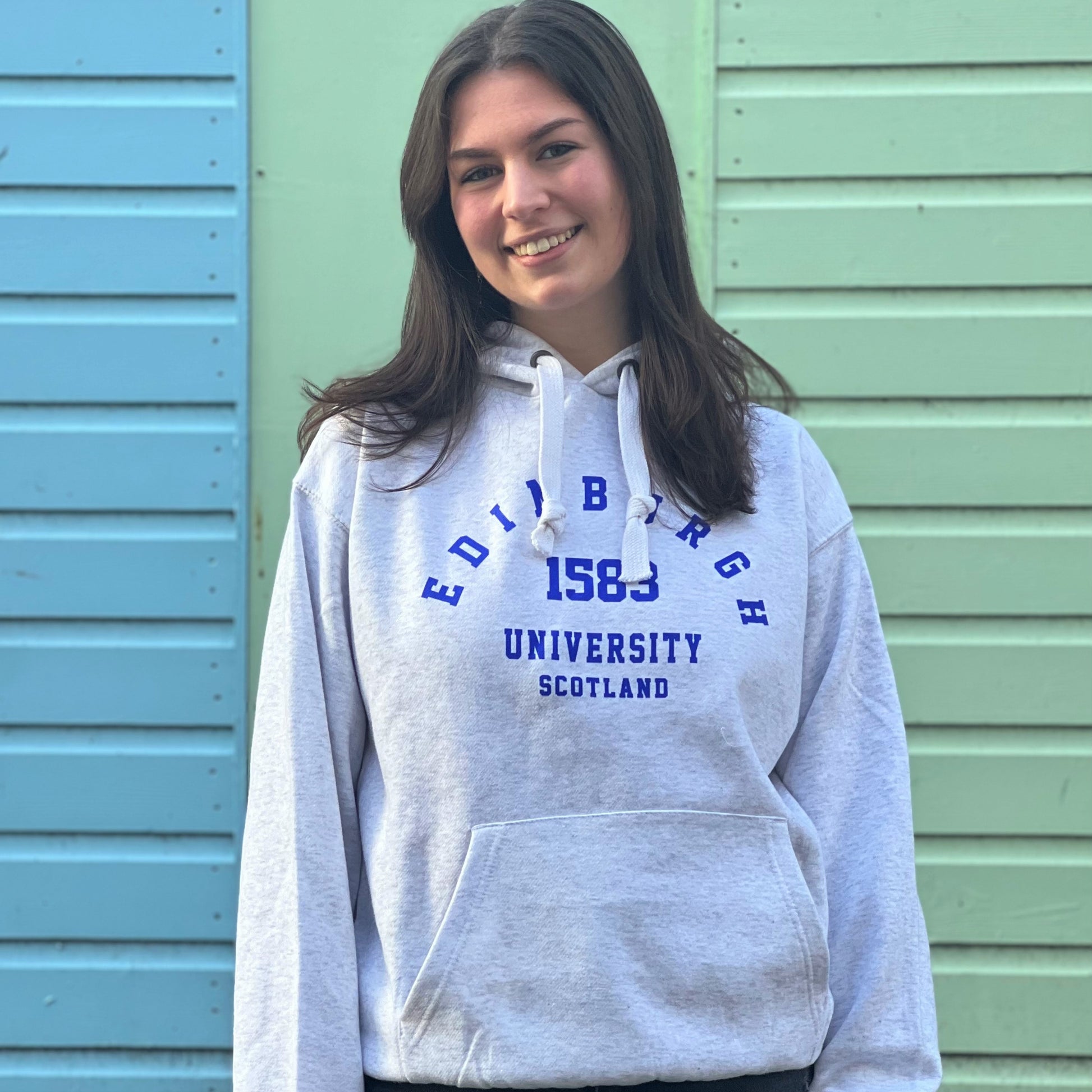 Our model wearing a Light Grey Hoodie with 'Edinburgh University 1583 Scotland' in royal blue print