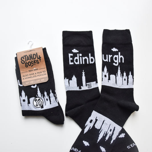 Black socks featuring the Edinburgh skyline in white print. 
