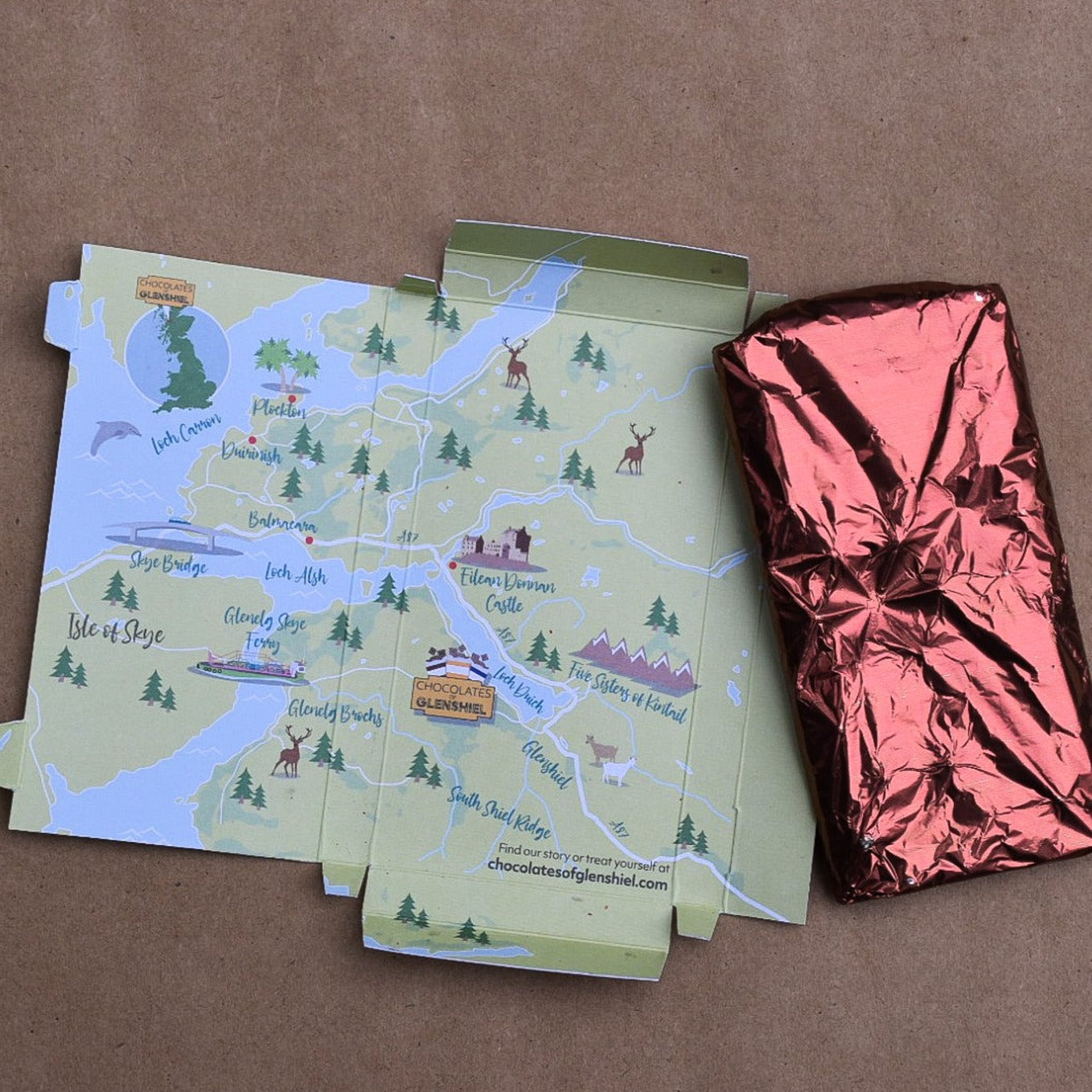 Chocolate bar in a foil wrapping displayed next to an opened chocolate bar package. The opened package has a design of the map of Glen Shiel Scotland on it.
