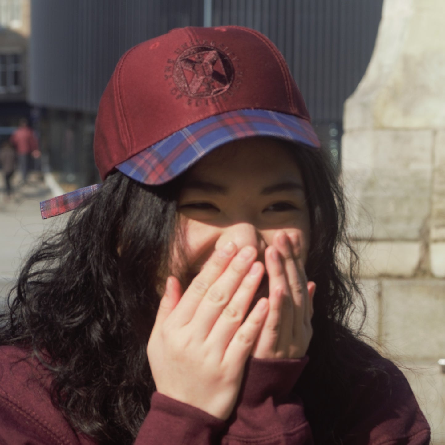 Our model wearing the tartan baseball cap outside, laughing.