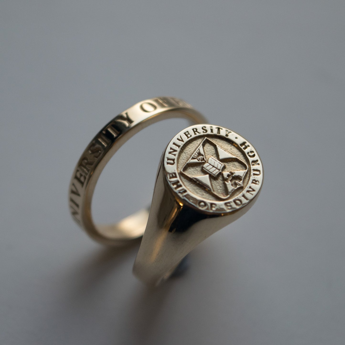 Gold graduation Signet Ring featuring the University crest with thin gold band ring behind